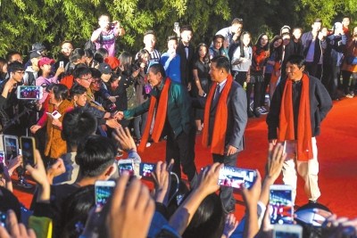 張藝謀走紅毯，不時(shí)與圍觀者握手致意。